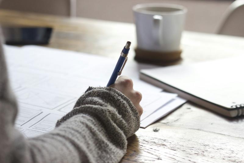 Graduate reviewing notes and laptop at a desk